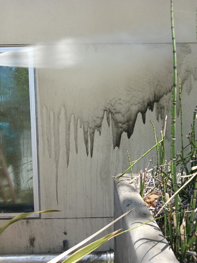 Dirty exterior wall being pressure washed