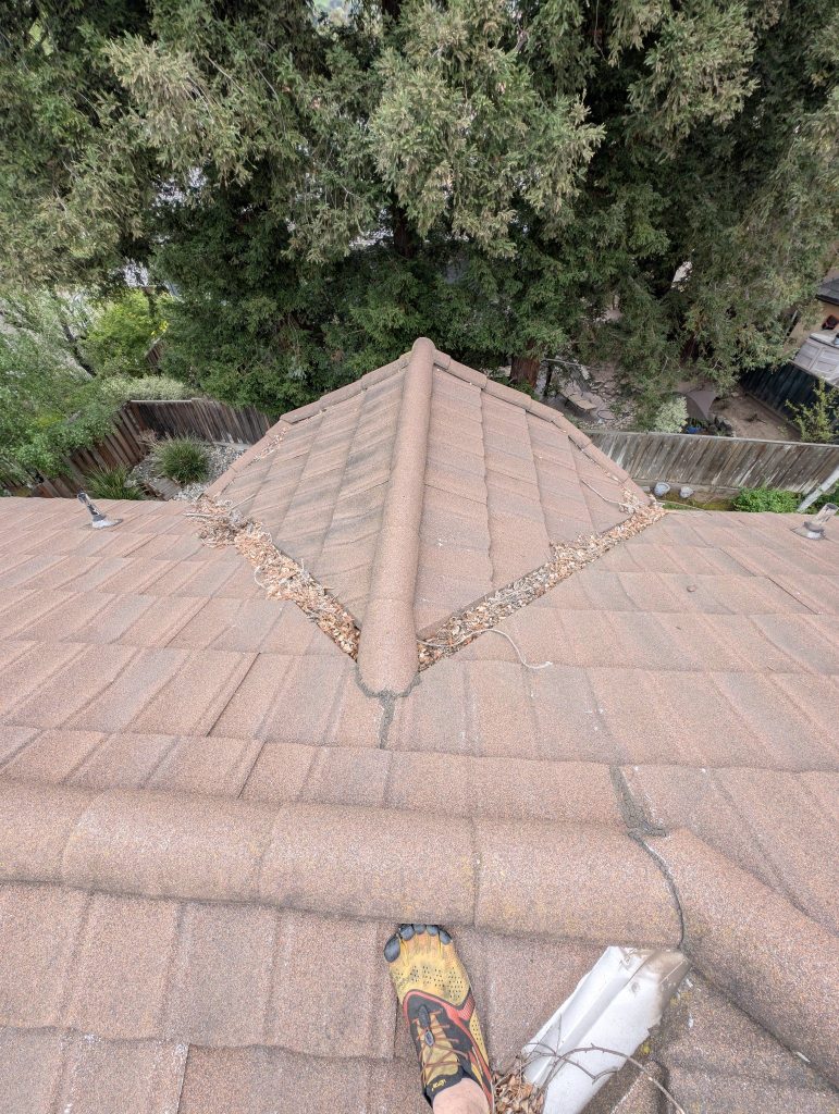 Tile roof valley packed with debris before cleaning