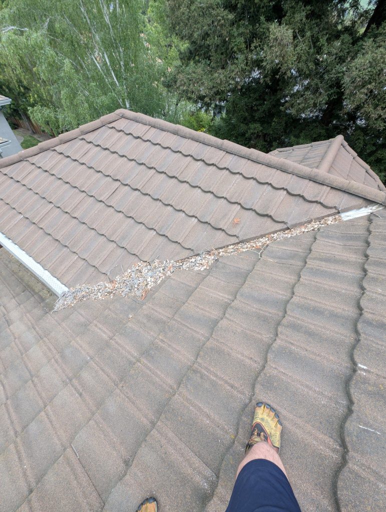 Roof valley full of packed debris before cleaning